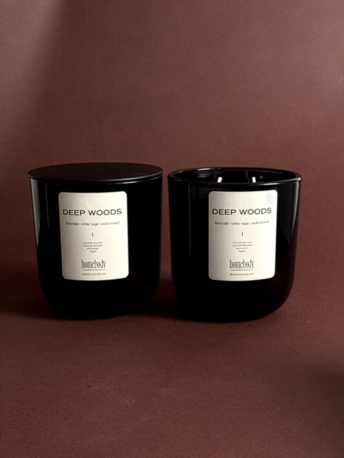 Two black fall candles labeled 'Deep Woods' on a brown background