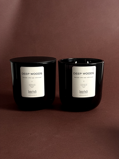 Two black fall candles labeled 'Deep Woods' on a brown background