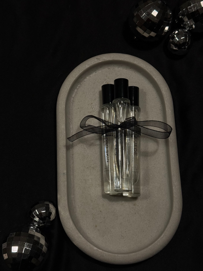 Set of small Perfume bottles with black caps on a gray stone surface, surrounded by decorative items.
